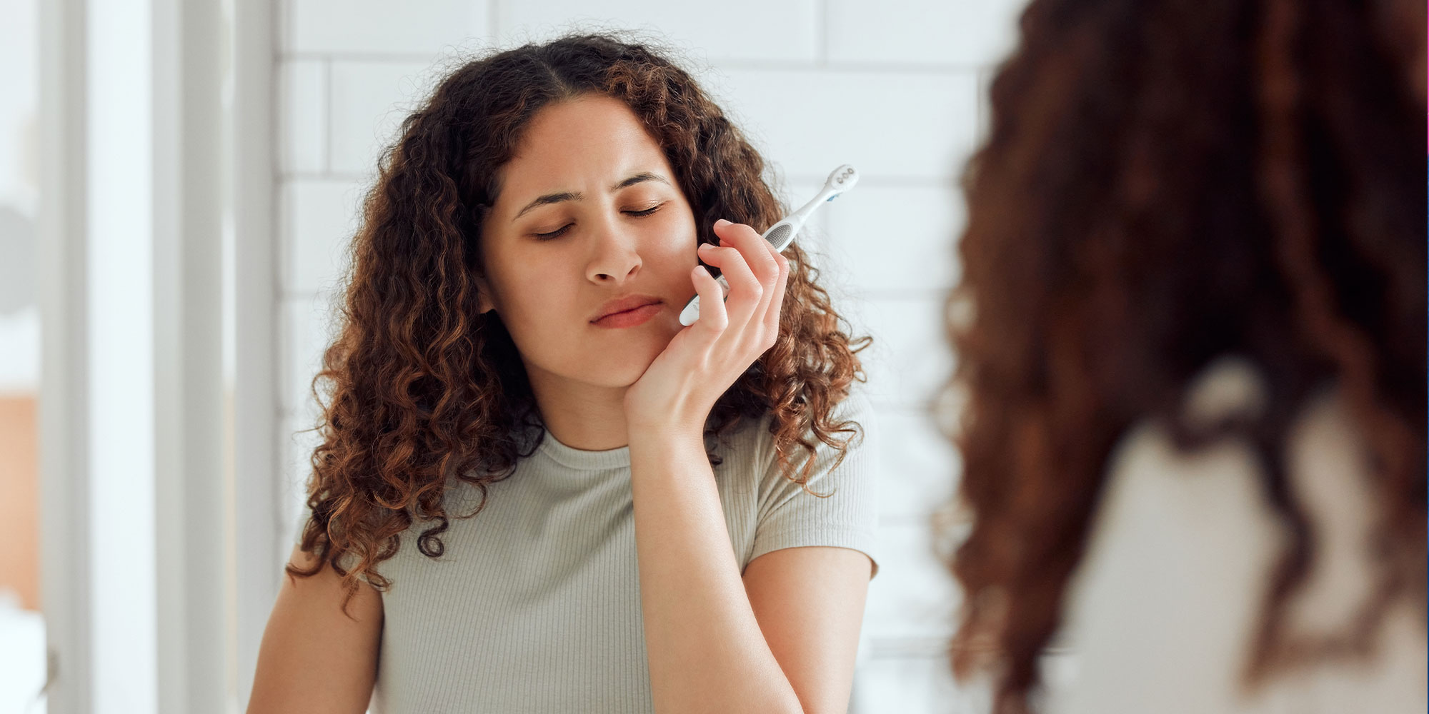 female having mouth pain while brushing their teeth