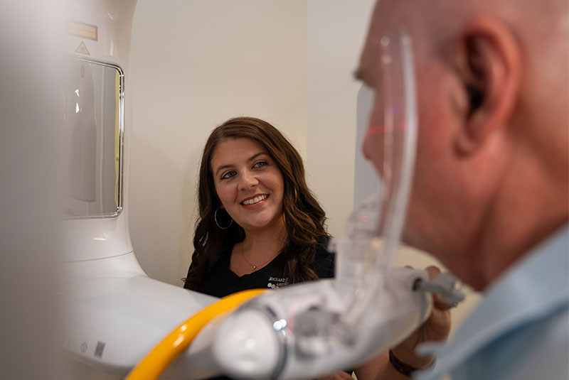 staff member helping dental patient go through a cbct scan