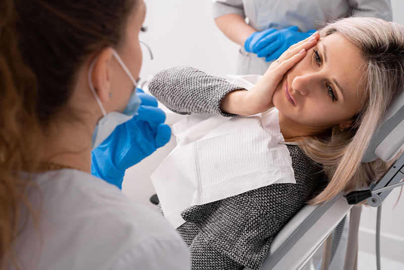 Professional dentist helps his female patient in pain