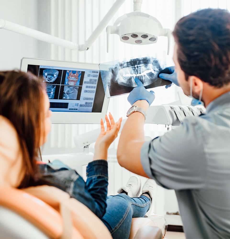 doctor looking over with dental patient x ray images for patient's treatment