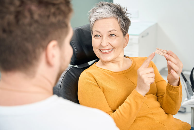 Woman client visiting dentist office to discuss dentures repairs